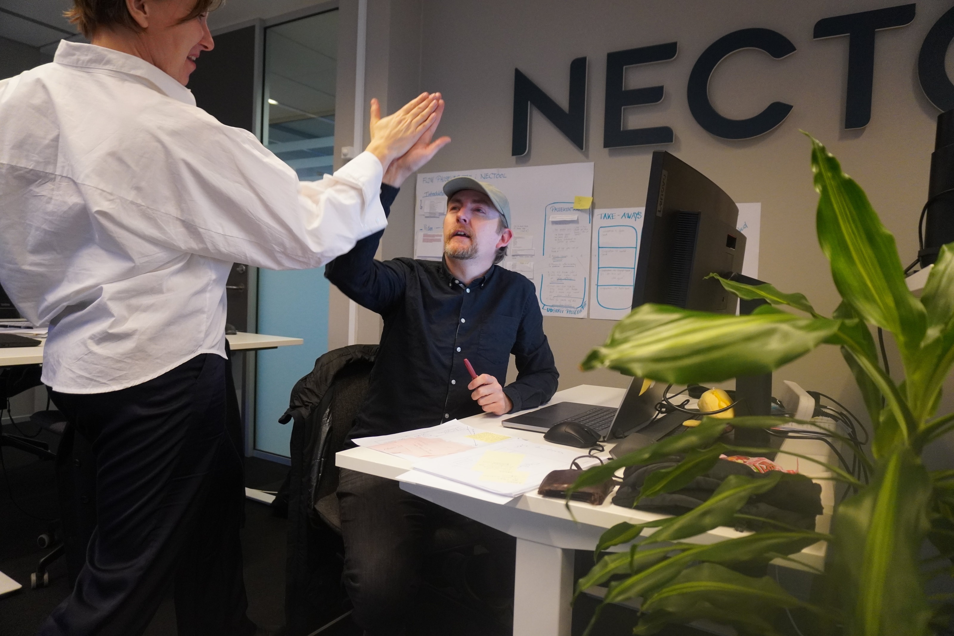 Two people high-fiving at a desk in an office
